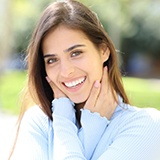 Young woman in blue shirt smiling outside