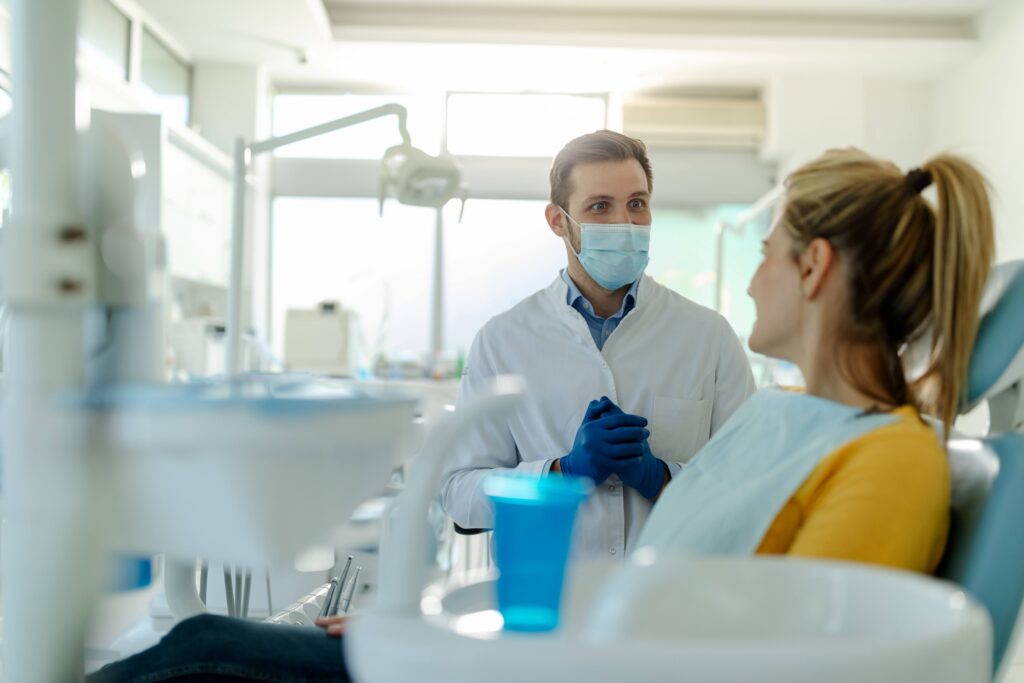 Dentist talking to smiling patient in treatment room